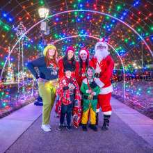 festive group of people with Santa under a light tunnel