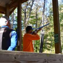 two men at a target clay shooting station in the woods