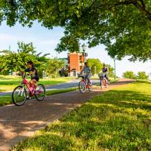 family riding bikes on a riverwalk