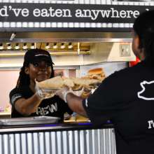 server picking up trays of food from a kitchen