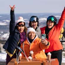 A group of skiers taking a selfie and enjoying a hot beverage