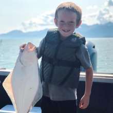 young boy holding halibut catch