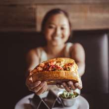 a very happy girl holding up a lobster roll at Rockfish Public House