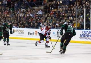 rapid city rush hockey player on the ice with local rapid city crowd in the background