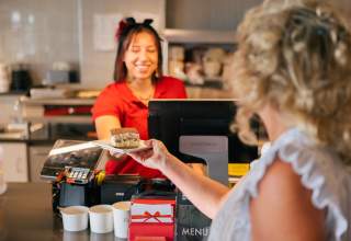 Woman behind the counter working at local lunch spot handing a desert to patron at The Bestro in Rapid City, SD.