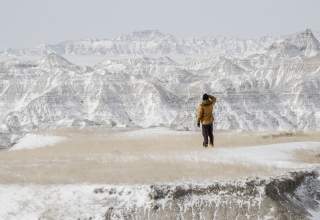 person exploring the beauty of badlands national park dusted in snow in the winter
