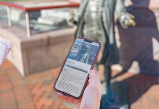 mobile phone looking at the audio tour app with president john adams statue in downtown rapid city