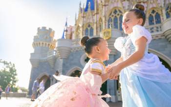 Two young girls dressed as princesses share a magical moment in front of Cinderella Castle at MAGIC KINGDOM AT WALT DISNEY WORLD Orlando