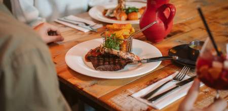restaurant table with steak dish, drinks and cutlery