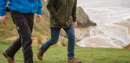 Legs of two walkers near the coast.