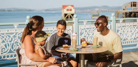 A family enjoying food outdoors on Mumbles Pier.