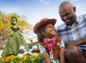 A family posing in front of a hedge statue of Bo Peep at the EPCOT® International Flower and Garden Festival