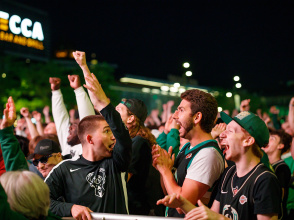 fans in a crowd cheering for the Bucks in playoffs at the Deer District