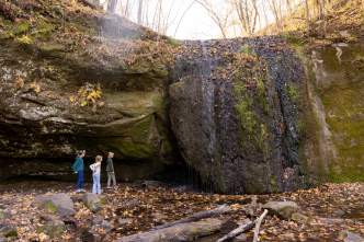 A wide image of children walking near a large rock formation at Governor Dodge State Park.