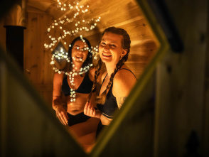 Looking through a sauna window at two women smiling.