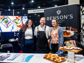 woman, man, and another woman smiling at a booth displaying lobster rolls and smores pie