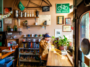 side view of a person sitting at a window drinking a cup of coffee at Sprocket Cafe