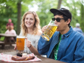 Two people at Hubbard Park Beer Garden, drinking beer over a large hot pretzel.