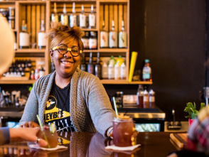 A bartender serving a non-alcoholic cocktail to two bar patrons.