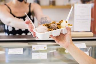 An employee at Ice Cream Social hands an ice cream flight to a customer