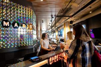 Two hotel guests check in with smiling front desk worker at The Moxy
