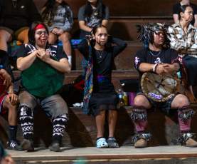 A group of people watching Indigenous dances in the stands.