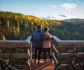 Couple taking in the view at Myra Canyon Trestles during Golden Larch Season 1