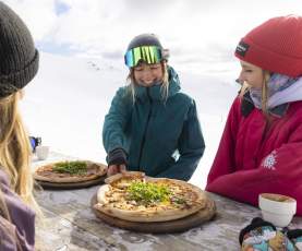 Friends eating pizza on the slopes at Cardrona Alpine Resort