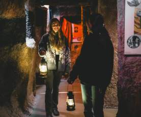 Two people, holding lanterns, walking through Nanaimo Museum's coal exhibit.