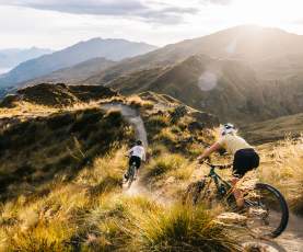 Two people riding mountain bikes through the mountains