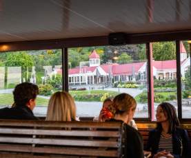 A group of people sitting on the TSS Earnslaw with a view of Walter Peak through the windows