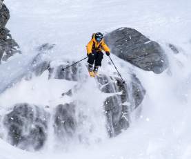 Freeskier Pete Oswald skiing down a rocky mountain face