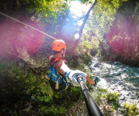 Person ziplining through a forest, over a river