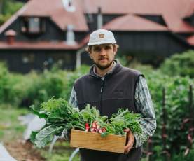 Man holding a box of radishes in the Sherwood Garden