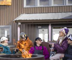 Group of friends sitting around a fire pit at Heidi's Hut Coronet Peak