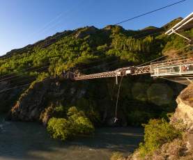 Wide shot of someone bungy jumping off a bridge over a river