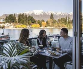 Three people Dining at Boardwalk with snowy mountains in the background