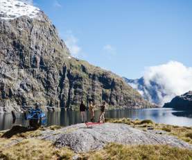 People having a picnic next to a high alpine lake with a helicopter next to them