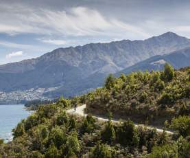 Person biking Jack's Point Trail, with Queenstown and Ben Lomond mountain in the background