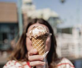 A woman holding a chocolate vanilla ice cream cone to the camera