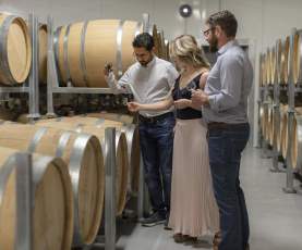 Guests sample wine during a guided barrel cellar tour at a West Kelowna winery in British Columbia’s Okanagan Valley