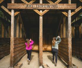 Two women getting ready to throw axes at a target