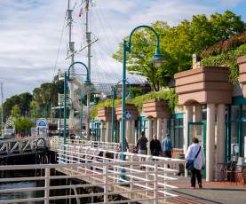 People walking along the harbourfront past shops.