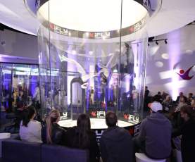 A group of people watching people indoor skydiving