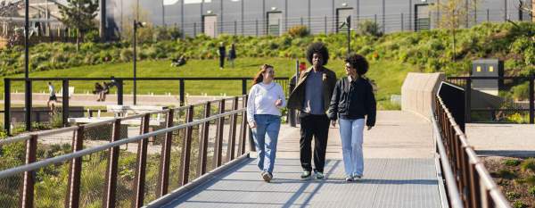 Friends walking along a bridge at Mayfield Park with Depot Mayfield sign in the background