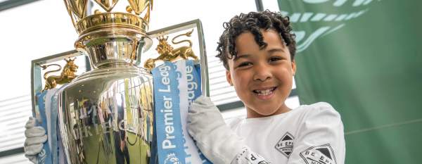 Young person holding up premier league trophy at National Football Museum in Manchester