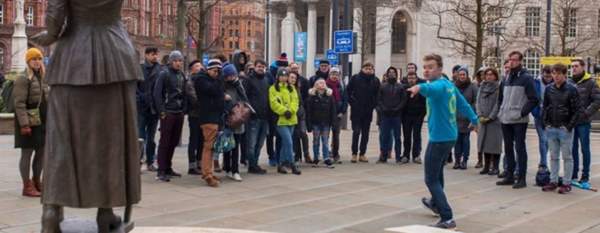 Group tour outside Manchester Central Library with tour guide pointing at statue of Emmeline Pankhurst