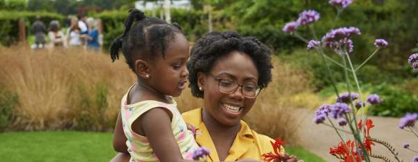 A woman holding a child looking at plants