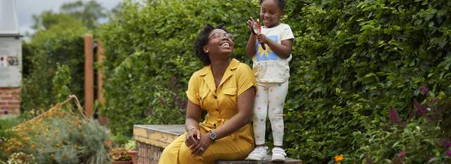 Adult and child sat on bench in front of plants at RHS Bridgewater