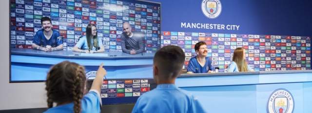 People sat in the press confeerence room on the Manchester City Stadium Tour